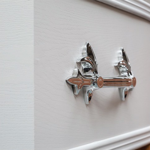 Chrome bar handle mounted on the panelled side of The Kedleston, shown in white
